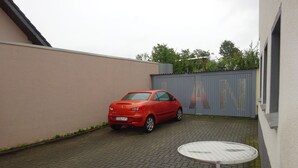 En röd bil står parkerad på en asfalterad innergård, med ett bord i förgrunden.