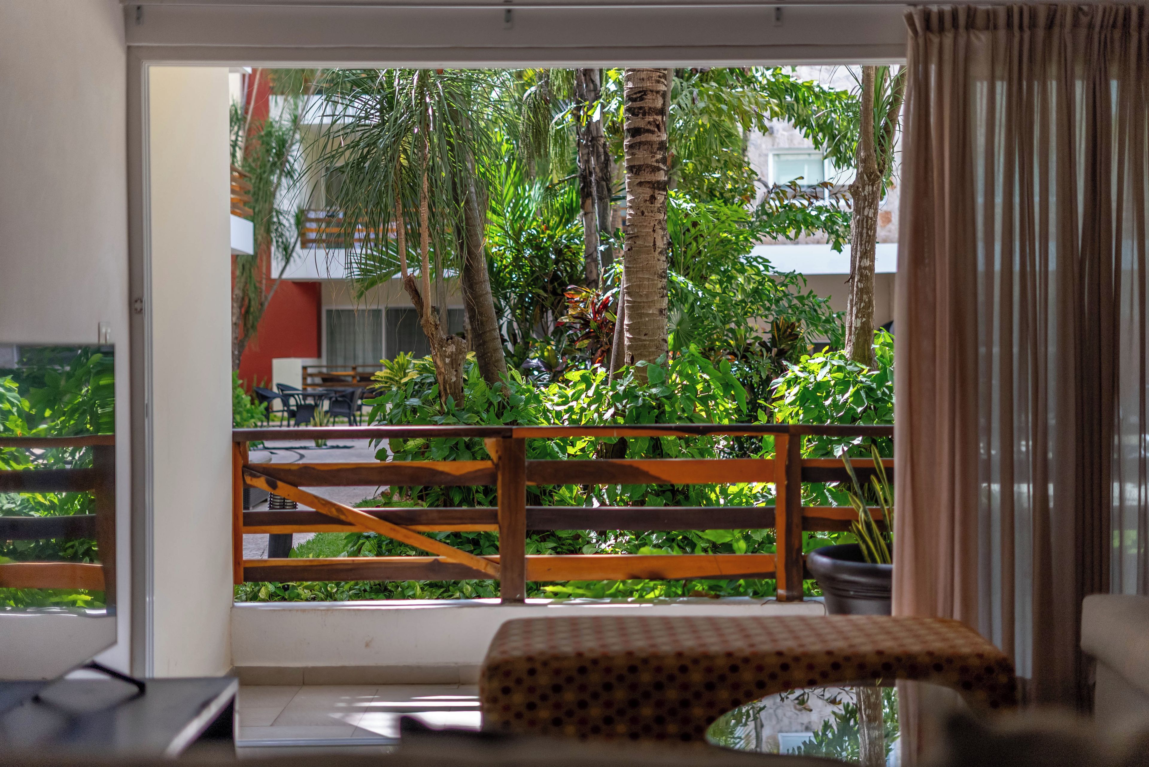 A room with a view of a balcony, a wooden railing, and a bench.