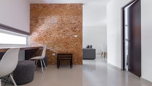 Un intérieur moderne avec un mur d’accent en pierre, un coin salon avec un banc et des chaises, et un design minimaliste.
