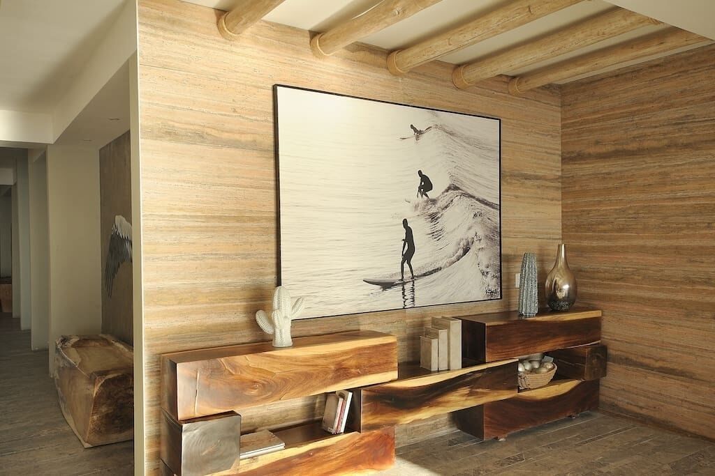 Ein modernes Interieur mit einem großen abstrakten Gemälde, Holzregalen und einer rustikalen Decke.