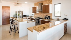 Een moderne keuken met een centraal eiland, ingebouwde apparatuur en een groot raam.