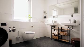 A modern bathroom with a toilet, a sink, a mirror, and a window.