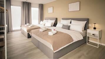Camera d'albergo con due letti, un comodino e un'ampia finestra con tende.