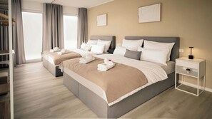 Une chambre d’hôtel avec deux lits, une table de chevet, une commode et une grande fenêtre avec des rideaux.