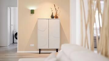 Ein modernes Interieur mit einem weißen Kleiderschrank, einer Wandleuchte und einer Vase mit getrockneten Ästen.