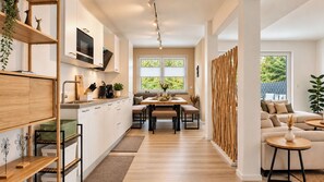 Une cuisine moderne avec un coin repas, un plancher en bois et une vue sur la verdure environnante.