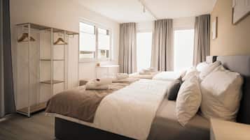 Habitación de hotel con una cama grande, un armario, un escritorio y una ventana con cortinas.