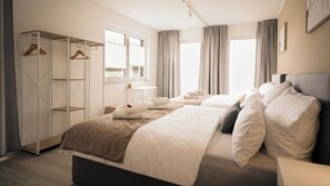 Une chambre d’hôtel avec un grand lit, une armoire, un bureau et une fenêtre avec des rideaux.