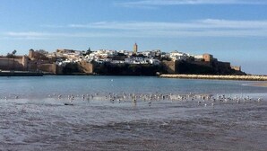 Un pueblo costero con una estructura fortificada y una playa en primer plano.
