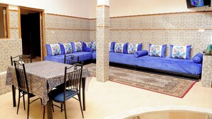Un comedor con una mesa y sillas, un sofá con cojines azules y un papel tapiz estampado.
