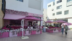 Un escaparate rosa con un letrero que dice "Cherie Cheru" y un letrero cercano de "Royal Burger".