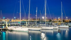 Un puerto deportivo con varias embarcaciones amarradas de noche, iluminado por luces artificiales.