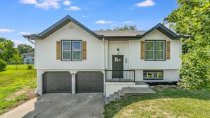 A two-story house with a front porch, two garage doors, and a small set of steps leading to the front door. - Large 4BR Home, Garage – Short & Long Stay (Pleasant Valley)