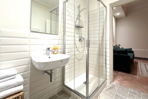A modern bathroom with a glass-enclosed shower, a white sink, and a mirror above it.