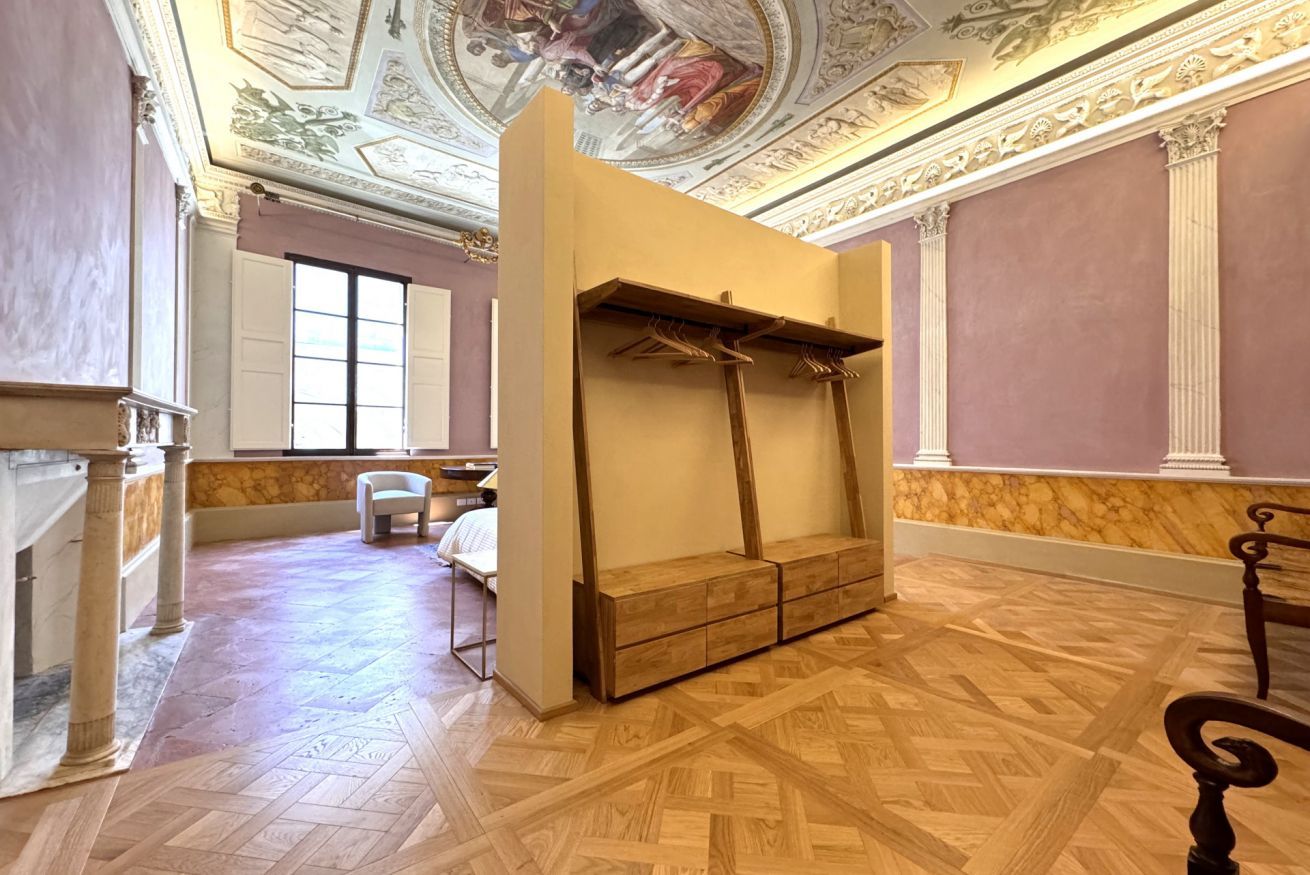 Een kamer met een houten bankje, een stoel en een bed.