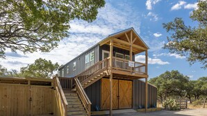 A two-story wooden building with a balcony, a staircase, and a covered porch.