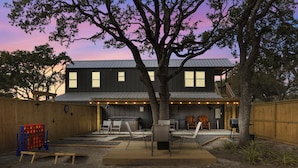 A backyard with a barbecue area, outdoor seating, and a large tree.