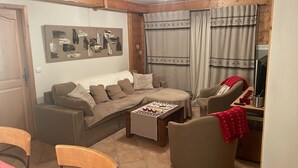 A living room with a sofa, armchairs, a coffee table, and a television.