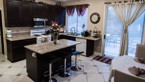 A modern kitchen with dark wood cabinets, granite countertops, a central island with bar stools, a microwave, and a sink. - 4Br Perfect 3,000 SqFt HOUSE 5st (LAS VEGAS)