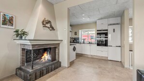 Una cocina moderna con armarios blancos, horno empotrado y chimenea con una escultura decorativa de un pájaro encima.