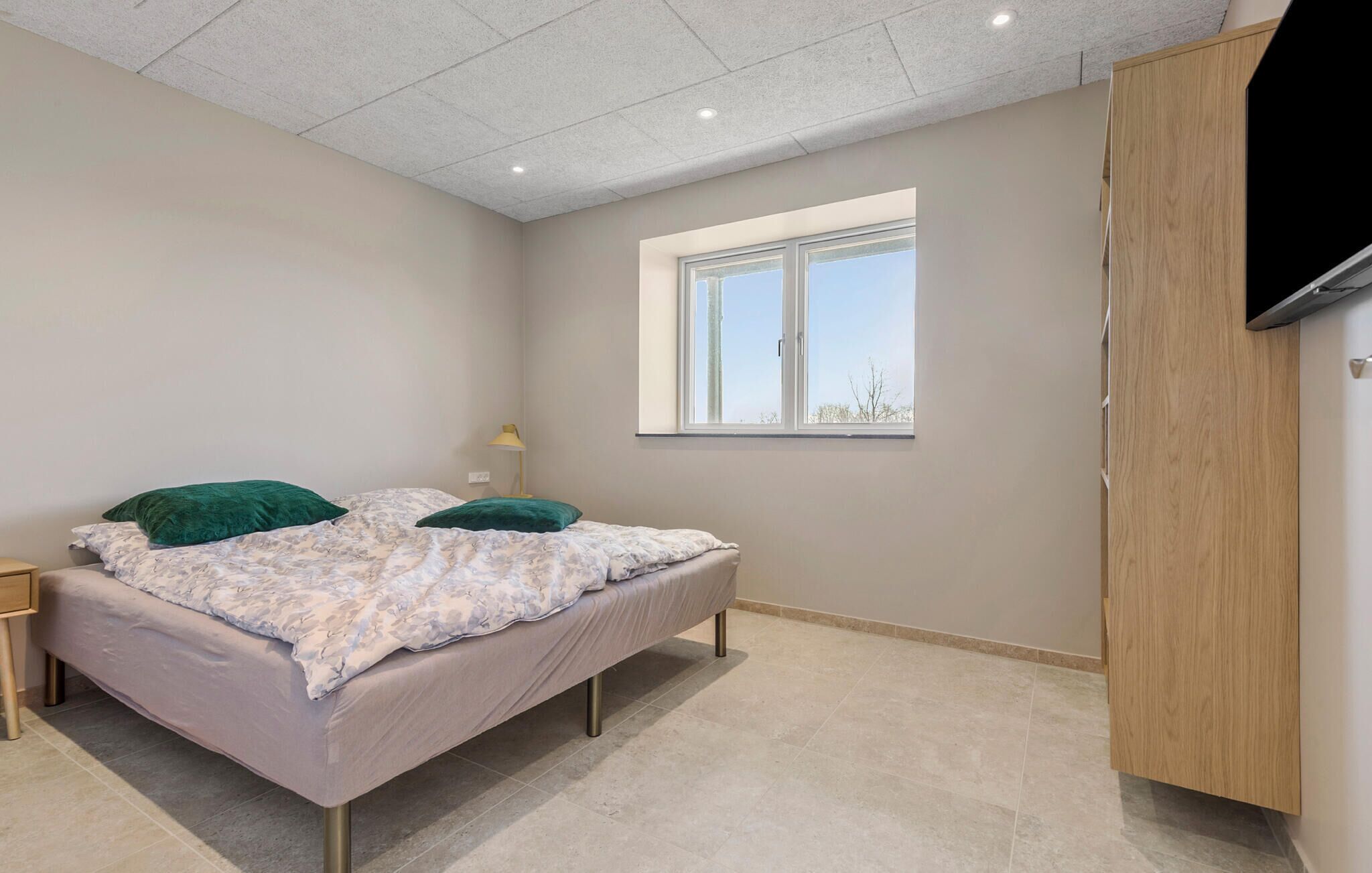 A bedroom with a bed, a nightstand, a window, and a wardrobe.