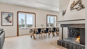 Un comedor amplio con una mesa larga, sillas, ventanas grandes y una chimenea.