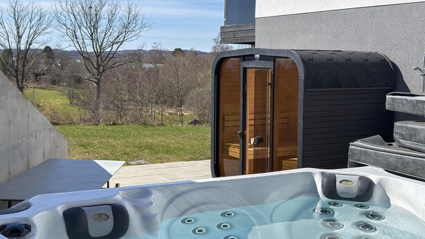 Un jacuzzi con múltiples chorros, una puerta de madera y vistas a un espacio verde con árboles.