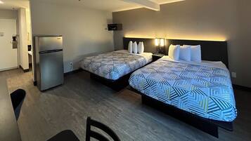 Habitación de hotel con dos camas, un refrigerador, un escritorio y una silla.