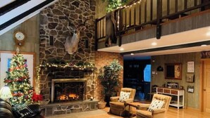 A cozy living room with a stone fireplace, a Christmas tree, and comfortable seating. - Raystown Mountain Escape - Views & Relaxing Spaces (James Creek)