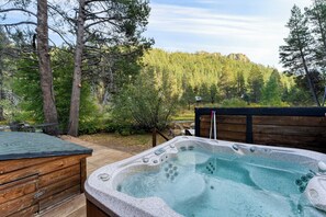 A hot tub on a wooden deck with a forest backdrop. - Riversong Lodge by Avantstay Sauna + Hot Tub On The Truckee River (Truckee)