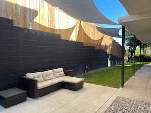 A modern outdoor seating area with a dark brick wall, a curved wooden structure, and a covered patio.