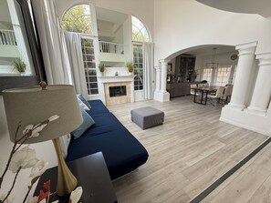 A spacious living room with a fireplace, a dining area, and a view of a balcony.