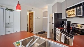 A compact kitchen with a stainless steel sink, a microwave, a stove, and a refrigerator. - 1st floor ski in & out resort condo with hot tubs, fitness room, covered garage. (Winter Park)