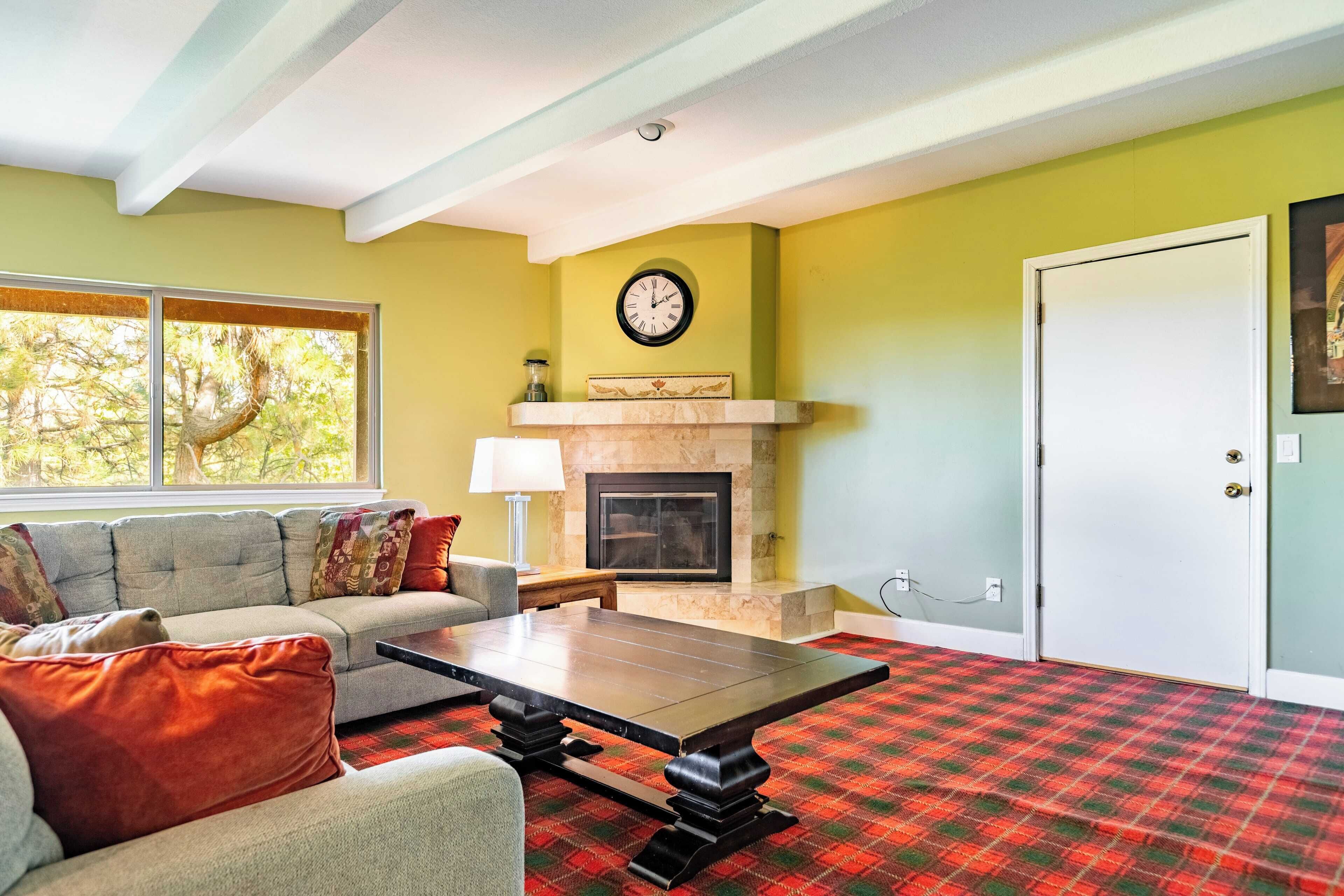 Un salon avec un canapé, une table basse, une cheminée, une horloge et une porte.