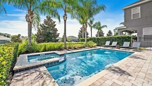 Ein Pool mit Whirlpool, umgeben von Palmen und einer Pflasterterrasse.