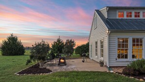 Une maison dotée d’un patio, d’un foyer extérieur et offrant une vue sur le ciel au coucher du soleil.