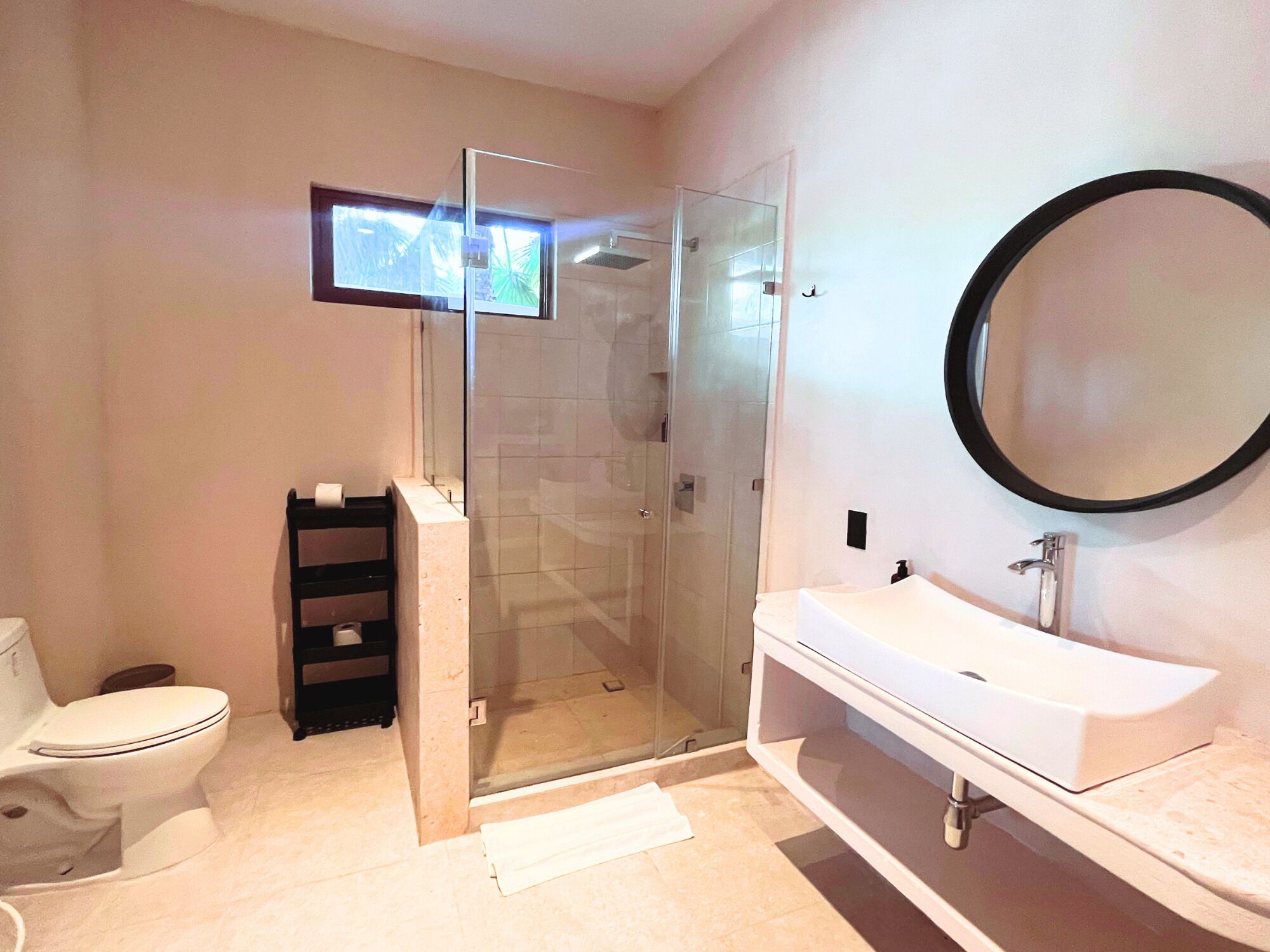 A modern bathroom with a glass-enclosed shower, a white sink, and a large mirror.