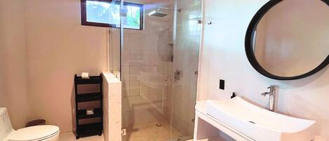 A modern bathroom with a glass-enclosed shower, a white sink, and a large mirror.