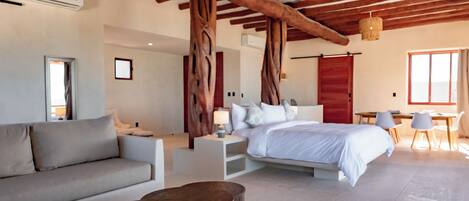 Ein modernes Schlafzimmer mit einem großen Bett, einer Couch, einem Holztisch und einer Essecke mit Stühlen.