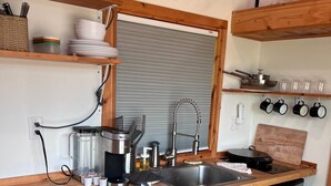 A compact kitchen with a wooden countertop, stainless steel appliances, and a small trash bin. - Secluded Tiny Home, firepit stargaze hike pond (Paige)
