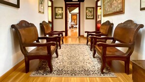 Un couloir avec des chaises en bois et un tapis à motifs, qui mène à une porte au fond.