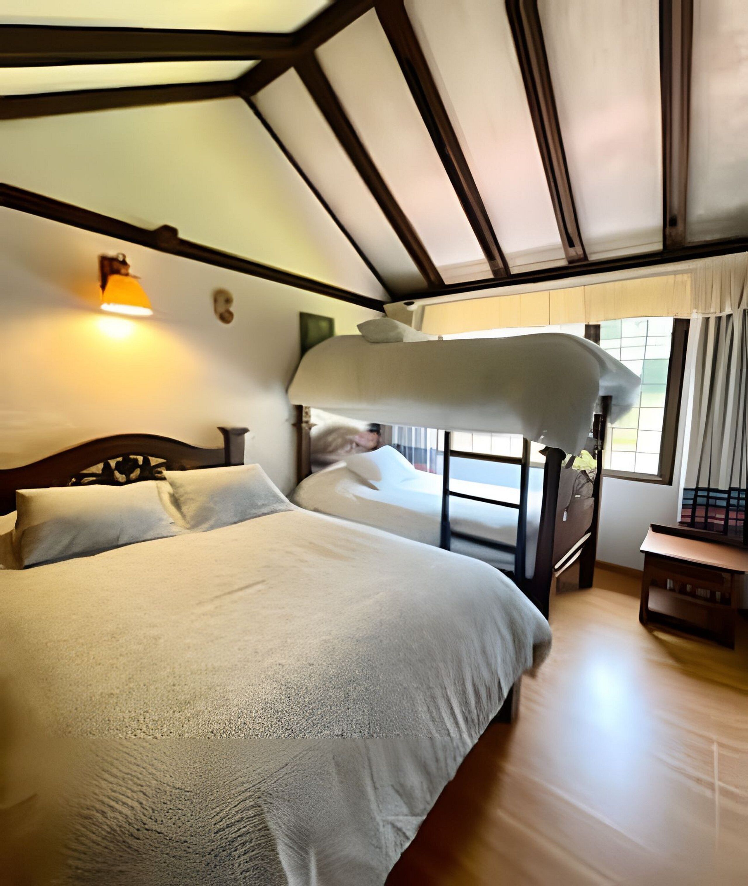 Un dormitorio con literas, una mesita de noche, una lámpara y una ventana con cortinas.