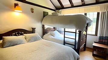 Un dormitorio con literas, una mesita de noche, una lámpara y una ventana con cortinas.