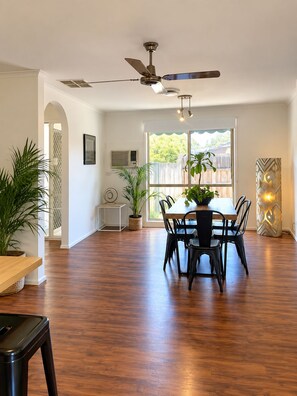 A dining area with a ceiling fan, a table with chairs, and potted plants. - Berwick Tweed - Peace and comfort (Melbourne)