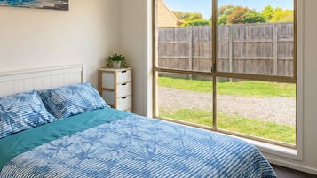 Une chambre avec un grand lit, une fenêtre et une vue sur un jardin.