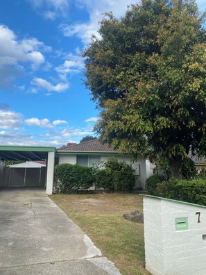 Um imóvel residencial com garagem, rampa de acesso coberta e uma grande árvore.
