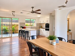 Cozinha moderna com ilha central, piso de madeira e área de refeições com cadeiras.