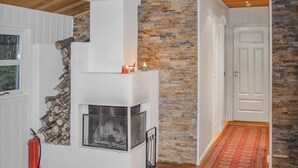 Ein Zimmer mit Kamin aus Stein, weißen Wänden, Holzboden und einem roten Teppich.