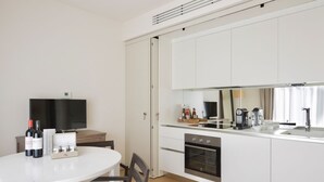 A modern kitchen with white cabinets, a built-in oven, and a dining area with a table and chairs.
