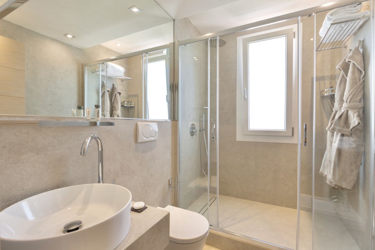 Un baño moderno con ducha de vidrio, lavamanos amplio y un inodoro.